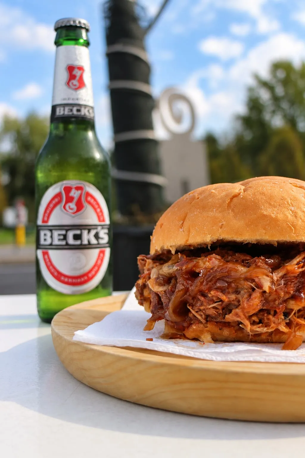 Panino con carne sfilacciata in salsa barbecue e una bottiglia di birra nel dehor